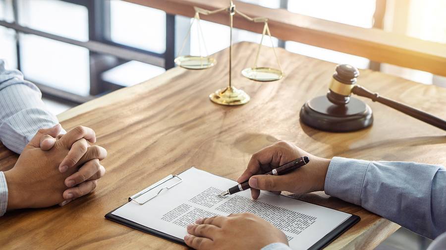 talking with a fort worth estate planning attorney at a wood desk with a gavel and scales of justice.