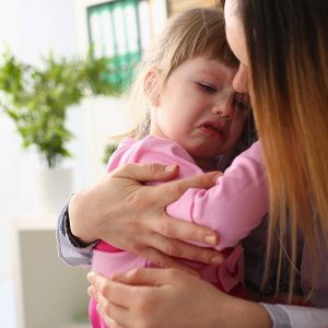 kid crying while being hugged by her guardian